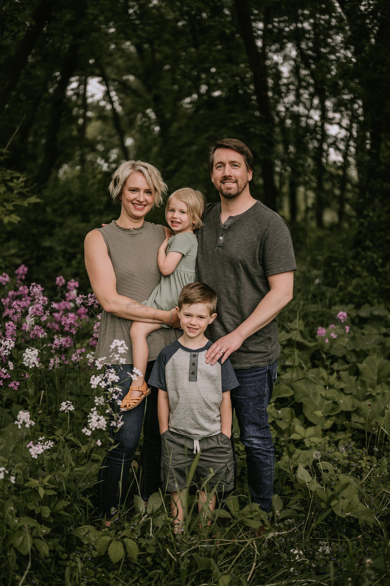Family portrait in a lush garden setting with purple wildflowers blooming.