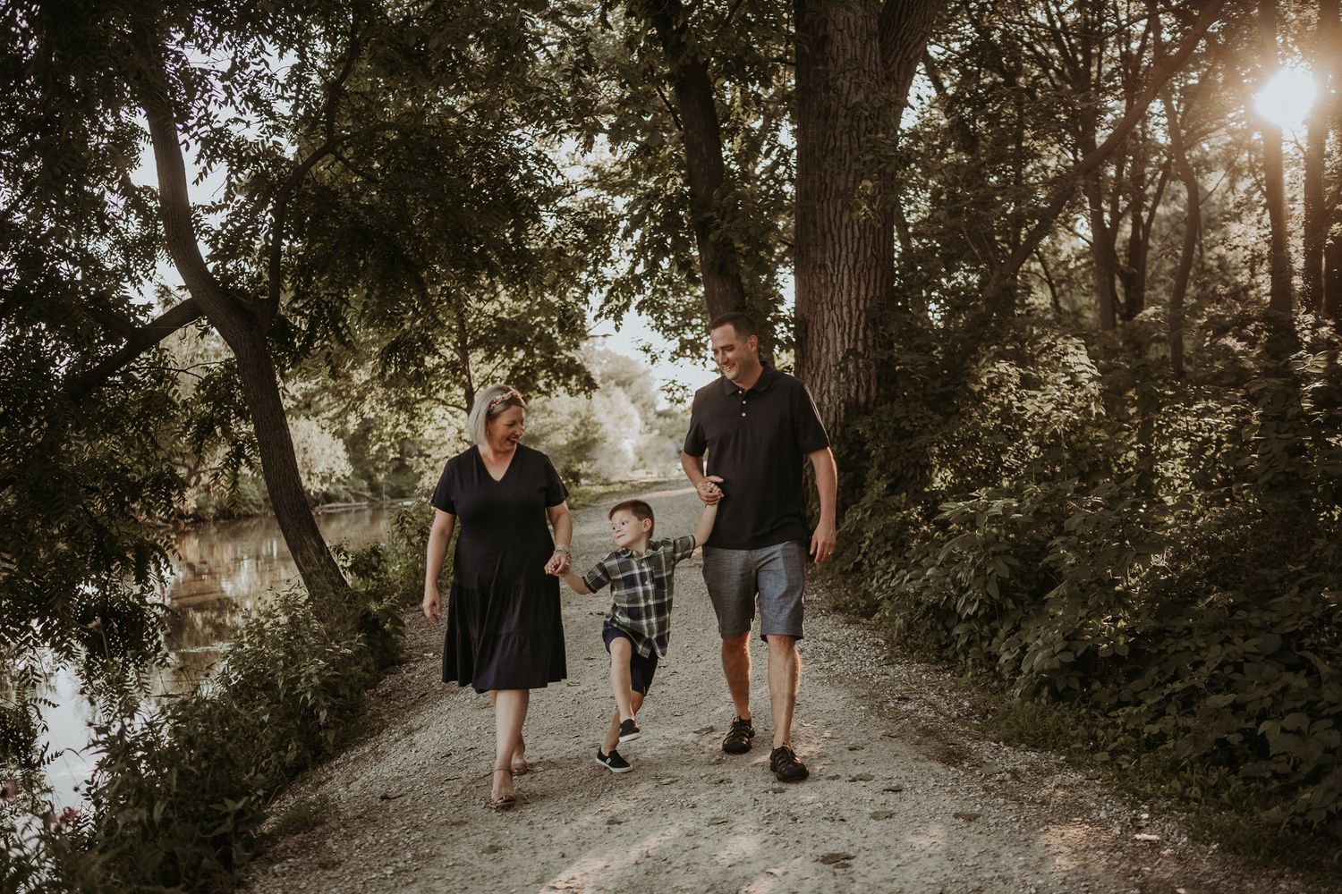 Family walking together on a tree-lined path during sunset.