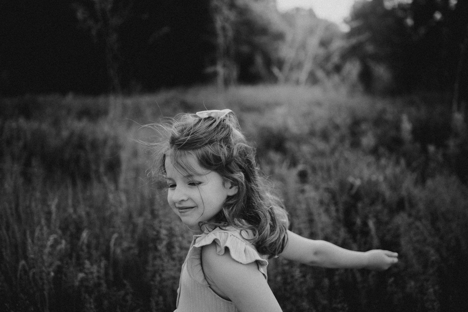 A joyful child spreads their arms wide while playing in a sunlit meadow.
