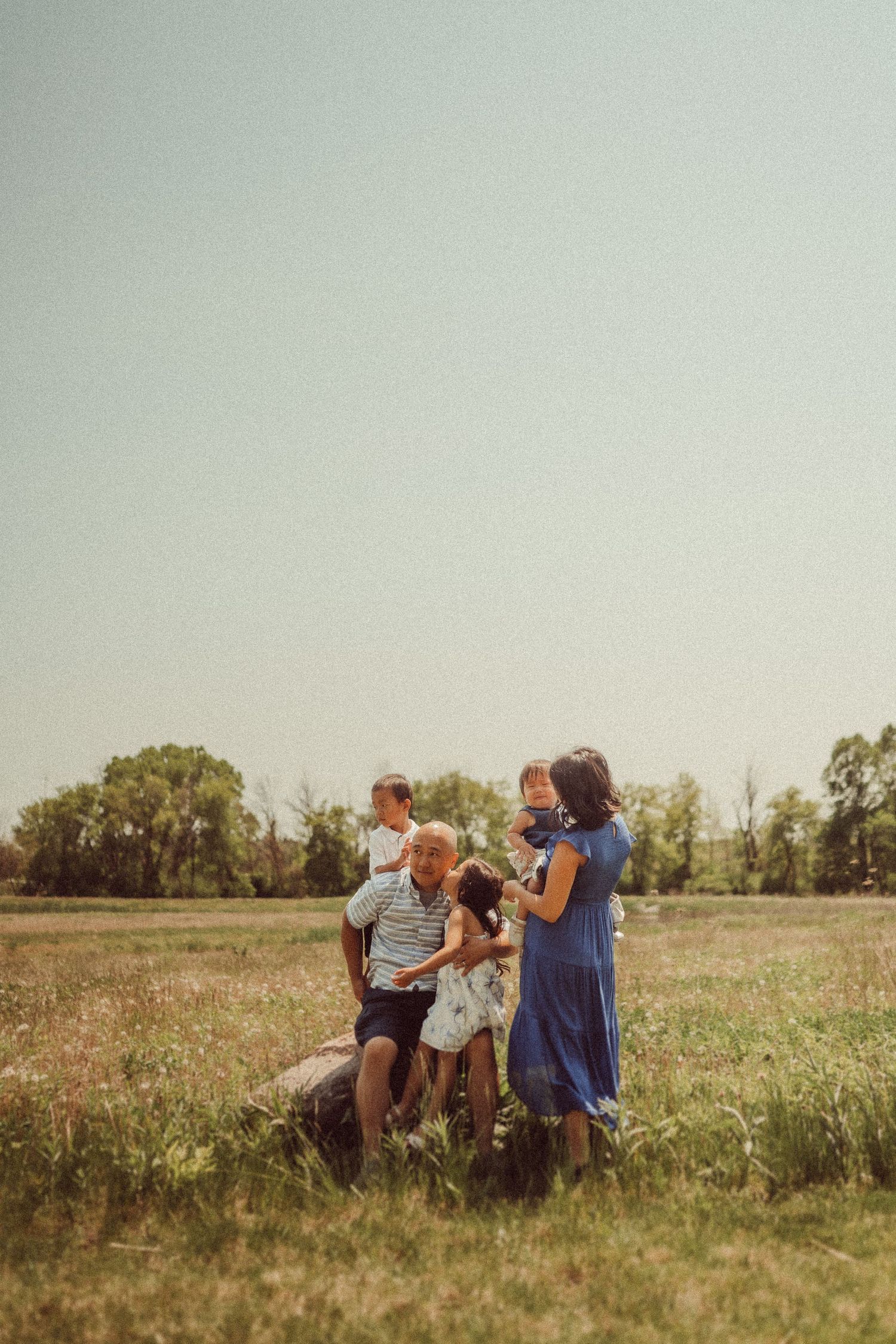 A candid family moment captured in a sunlit meadow.