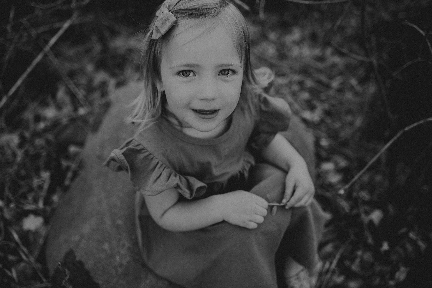 Black and white portrait of child smiling during outdoor photoshoot.