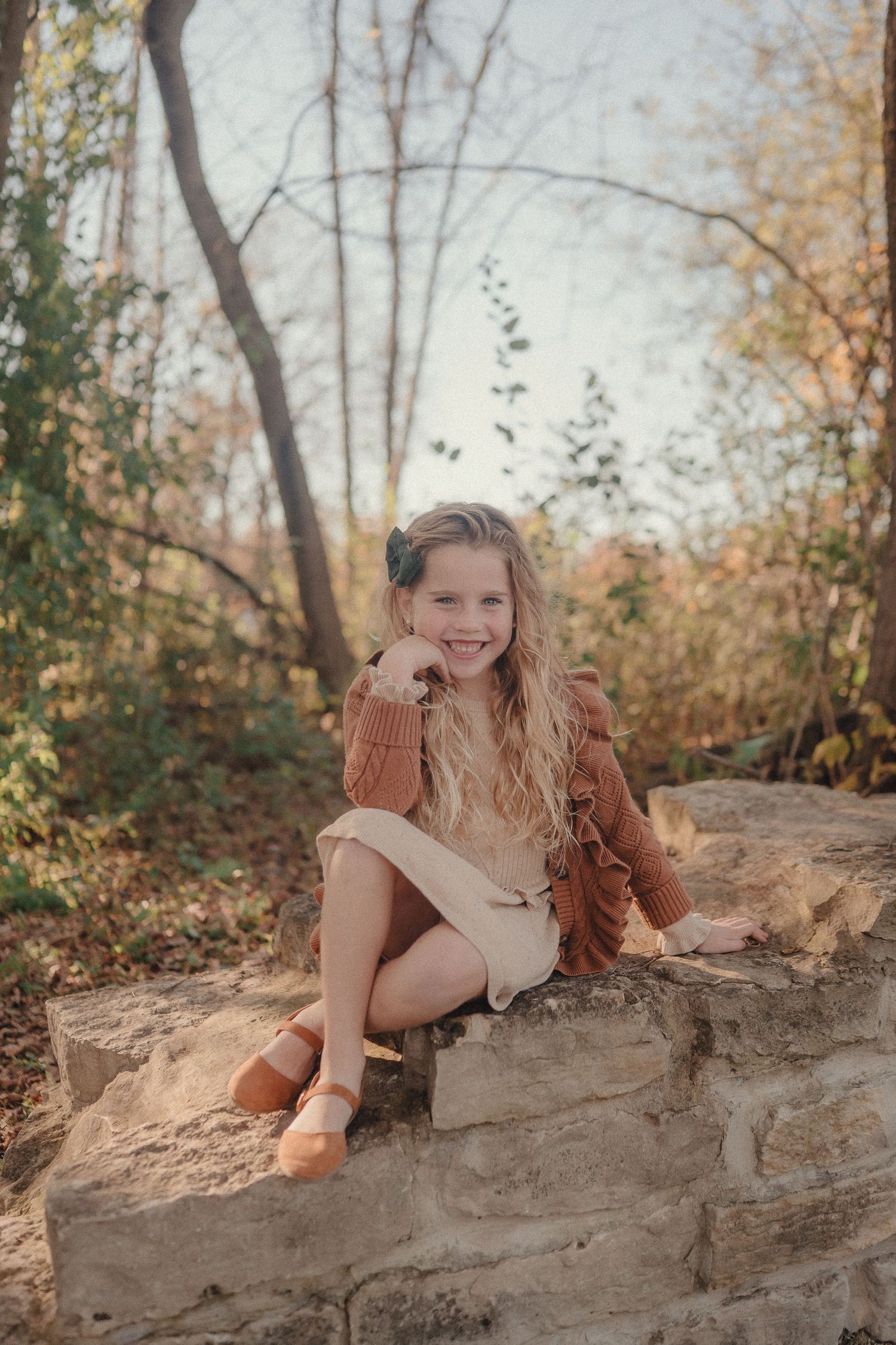 A series of autumn outdoor portrait photos showing someone posing playfully on a stone wall among fall foliage.