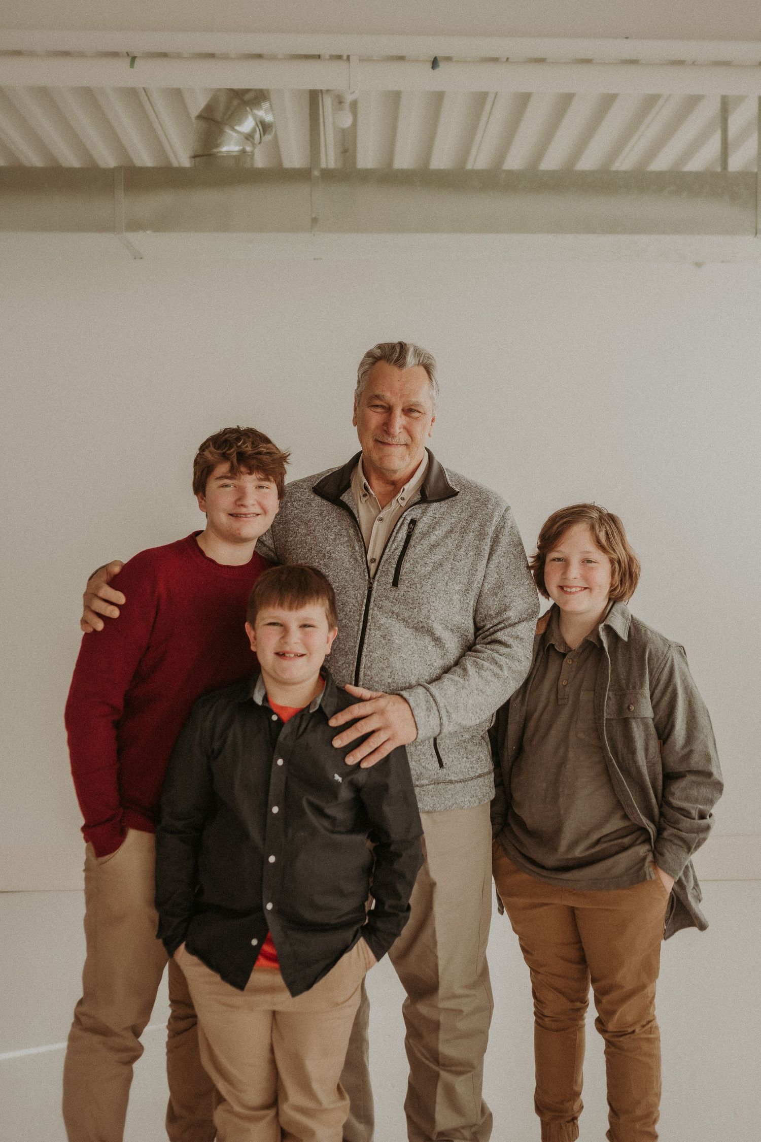Four people pose together against white studio wall for casual family portrait.