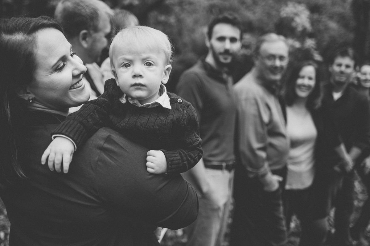Black and white photo of family line-up outdoors with trees in background.
