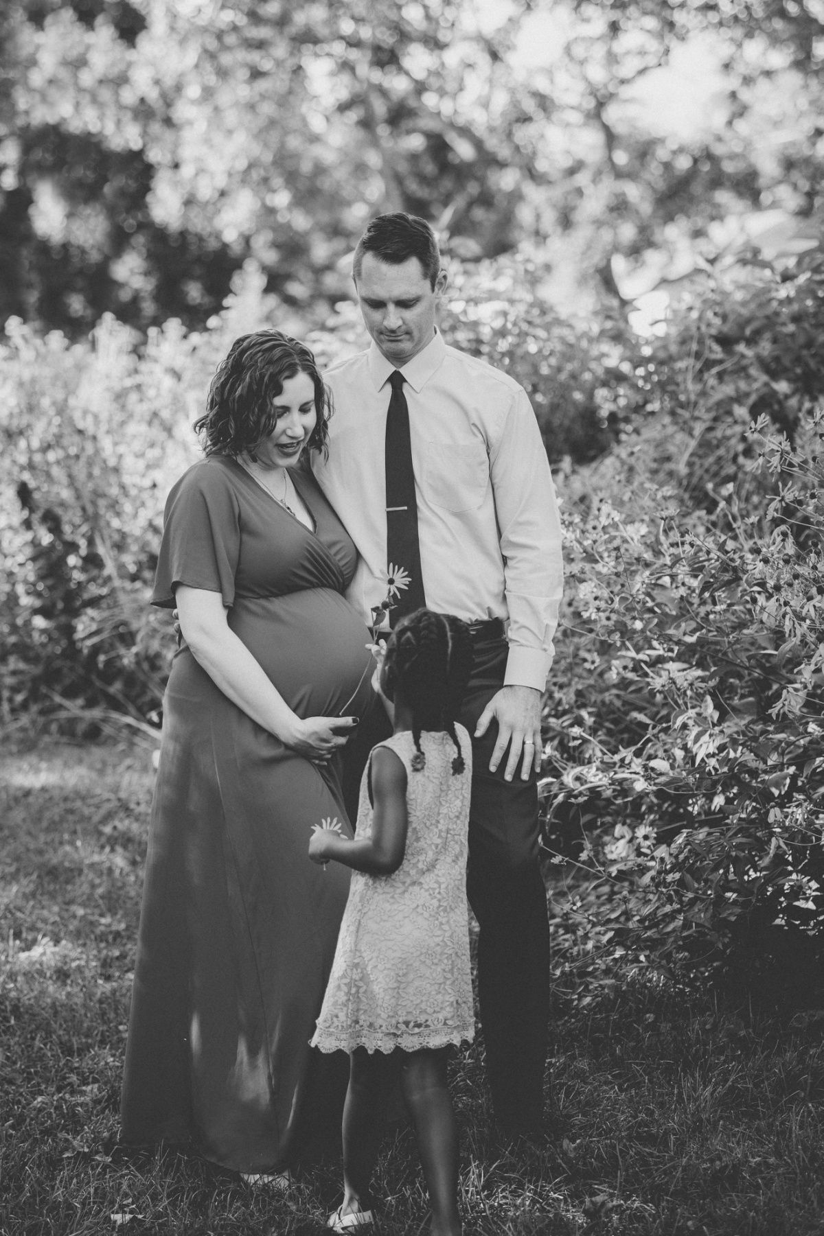 Black and white family portrait in garden setting with long dresses.