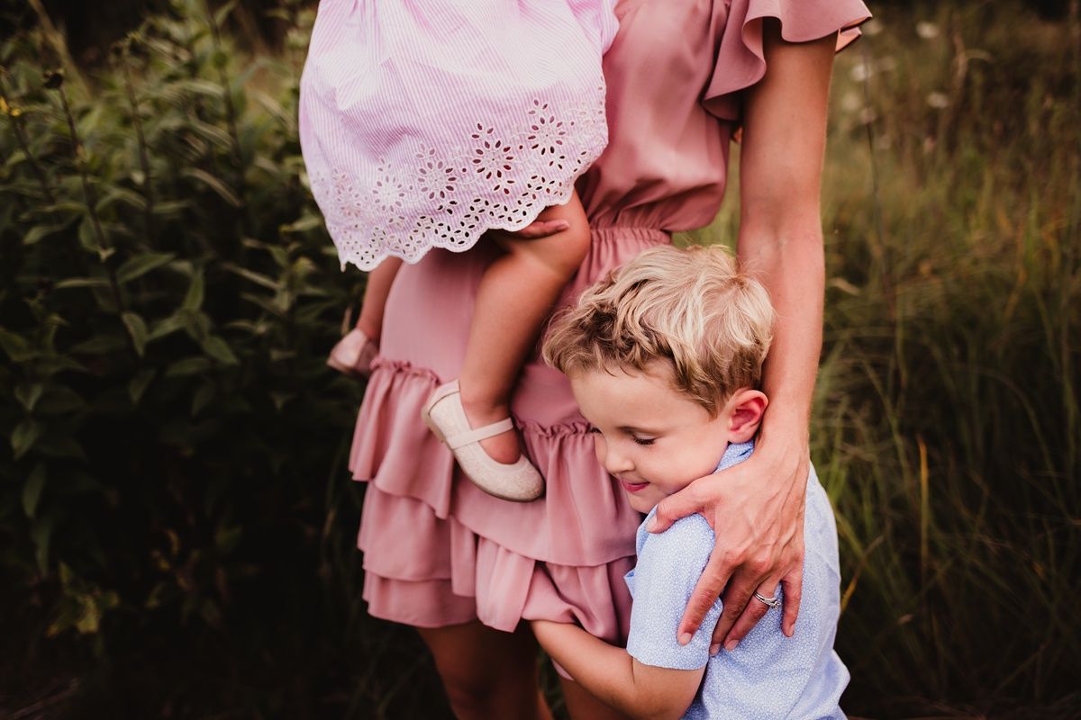 Intimate family portrait showing tender moments in a field at golden hour.