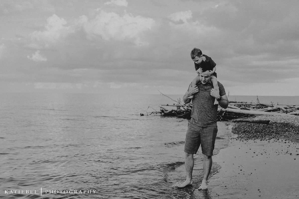 Black and white beach scene with waves lapping at shore during family photoshoot.