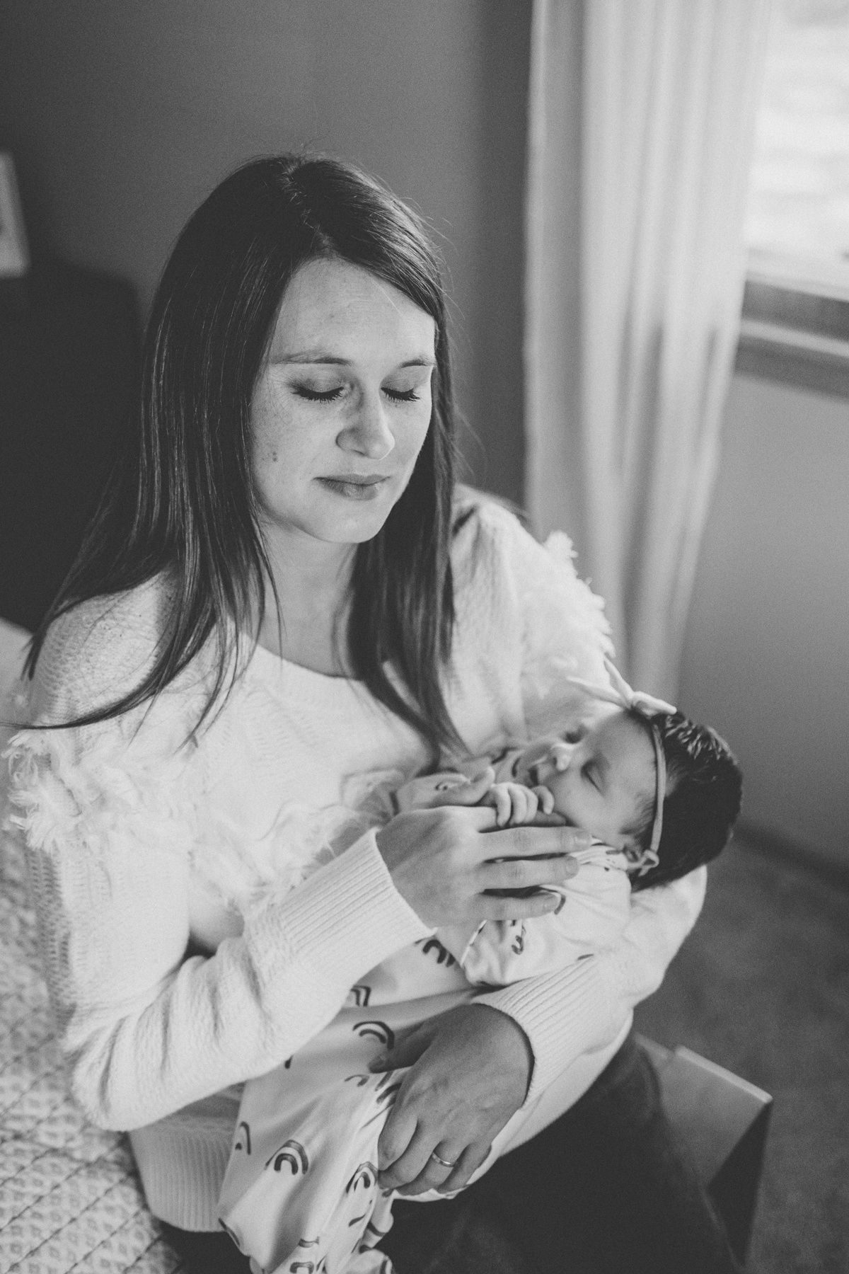 Softly lit black and white portrait of nurturing moment with infant.