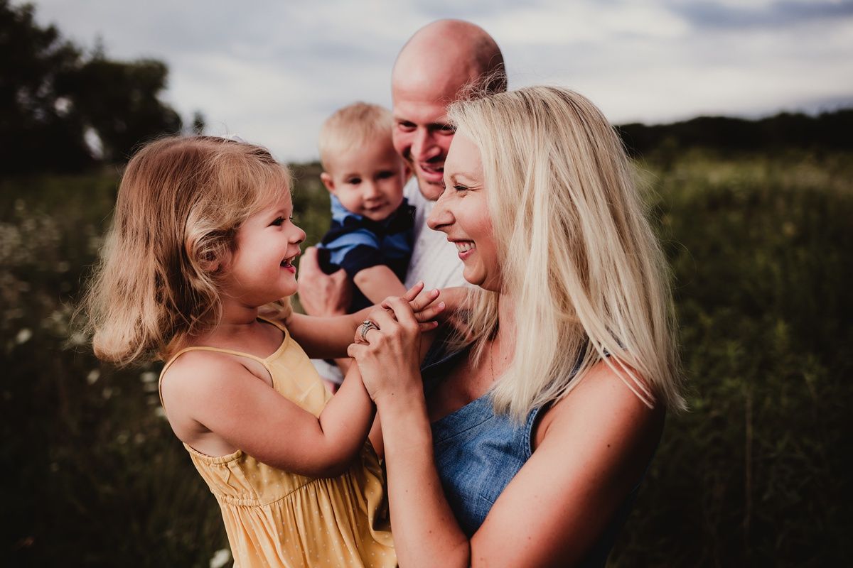 Joyful family moment captured outdoors during golden hour in a summer field.