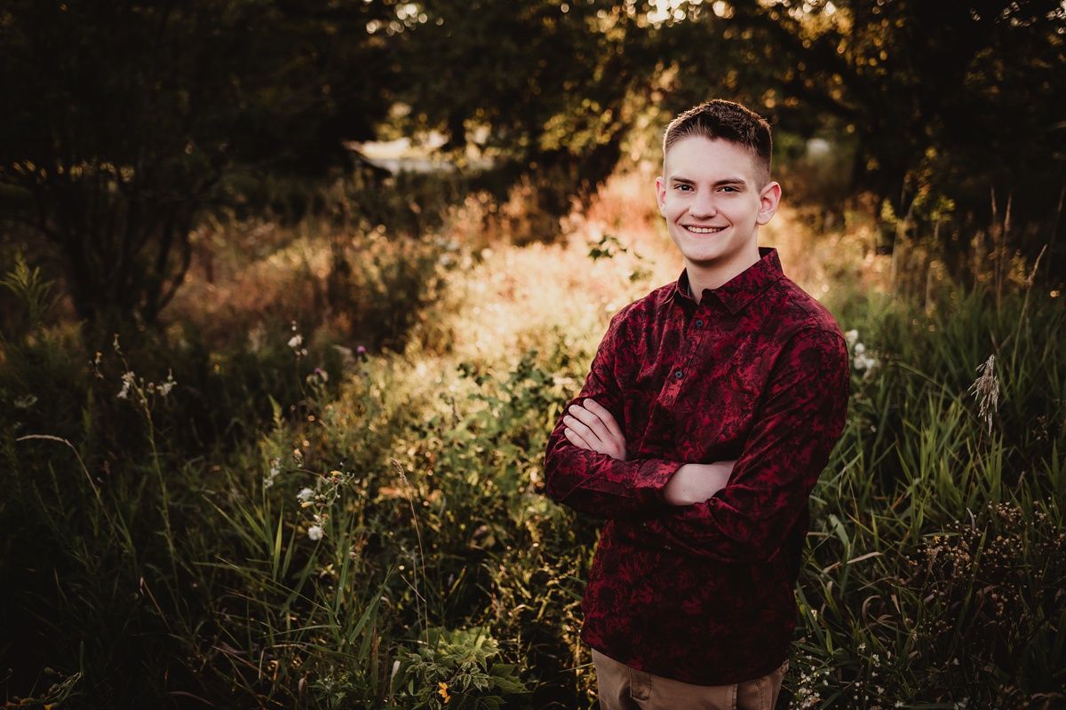 A portrait of a person in a burgundy sweater standing in golden evening light.