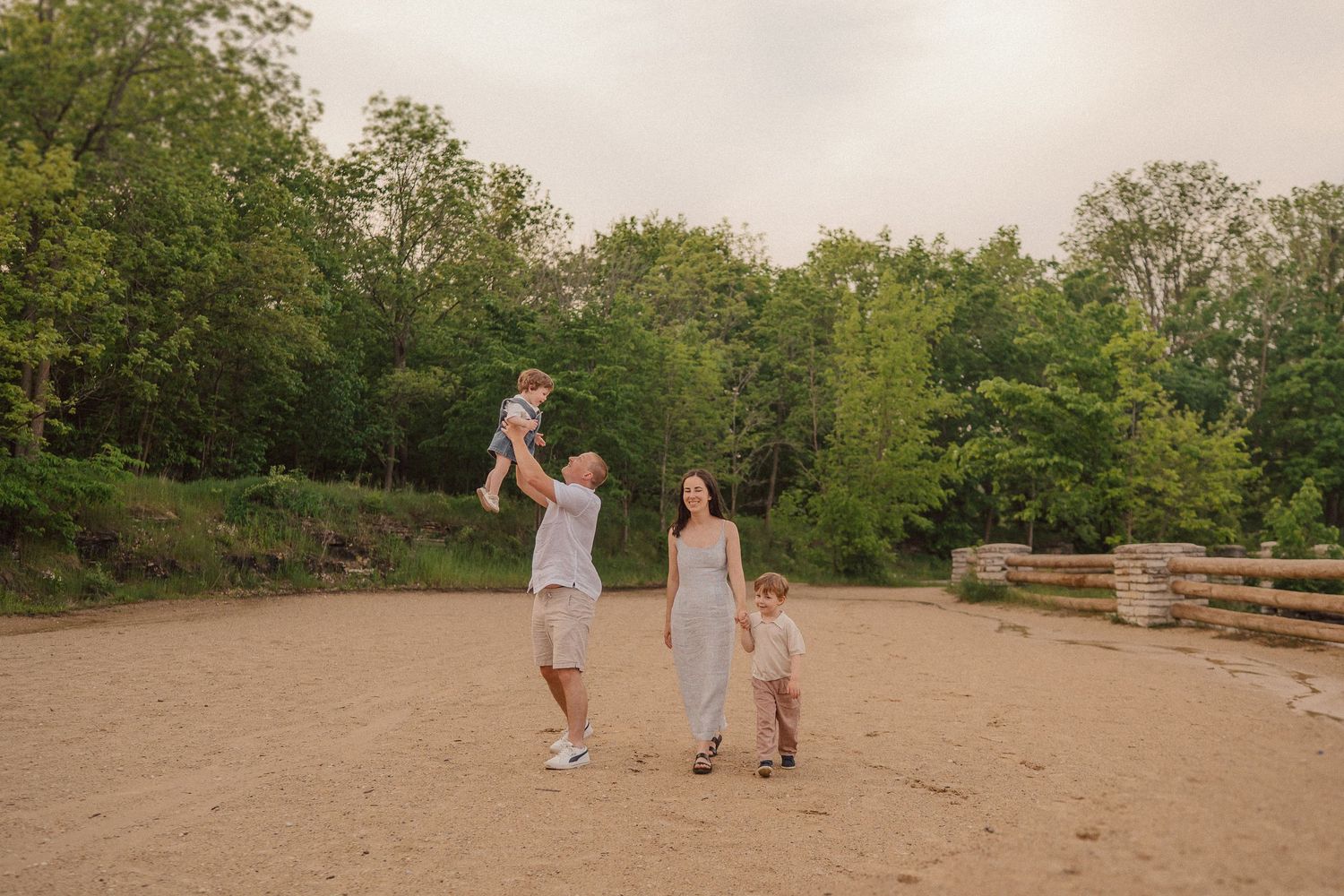 Family enjoying a playful moment together in an open field during golden hour.