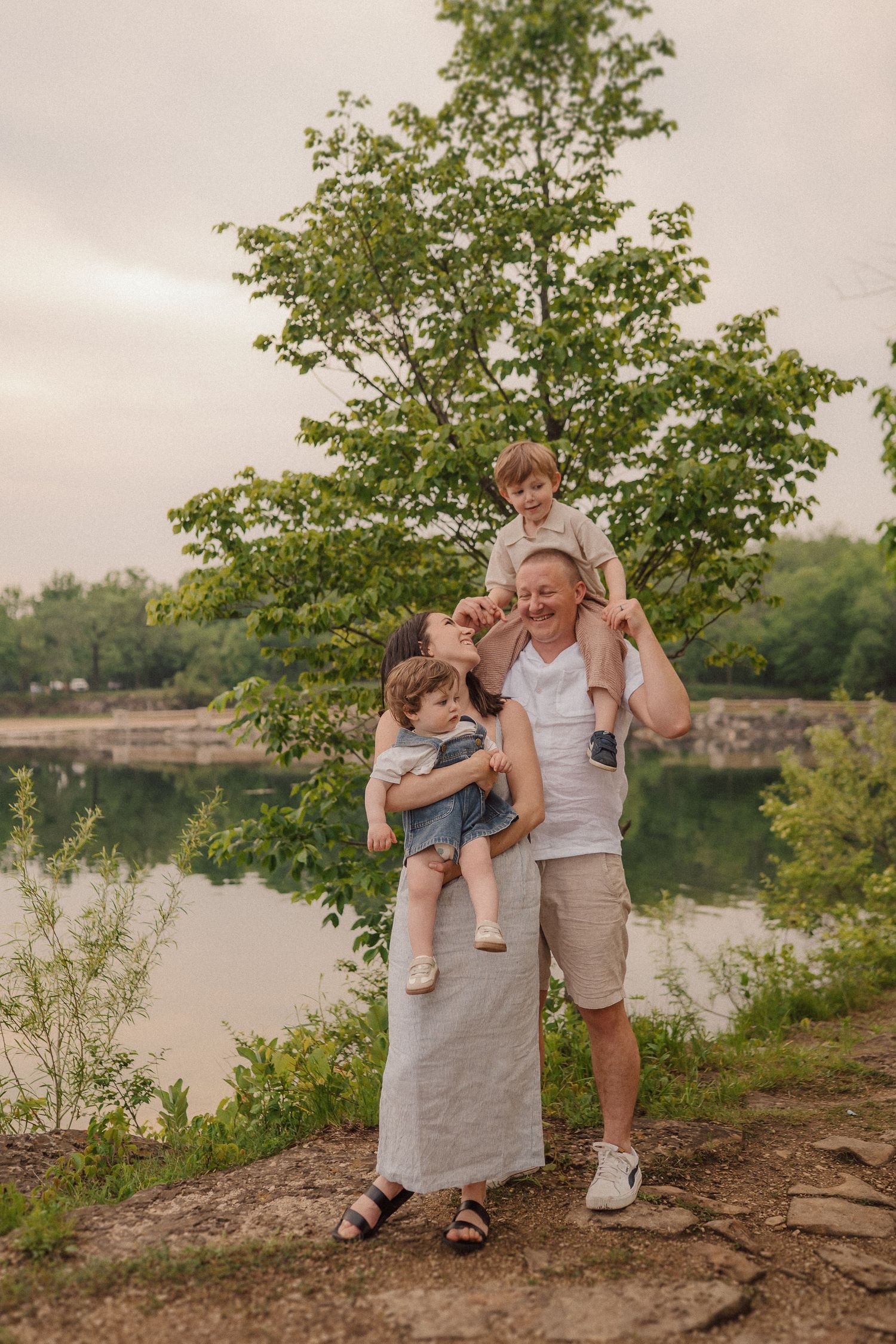 Family shares intimate moments together by lake during golden hour photo session.