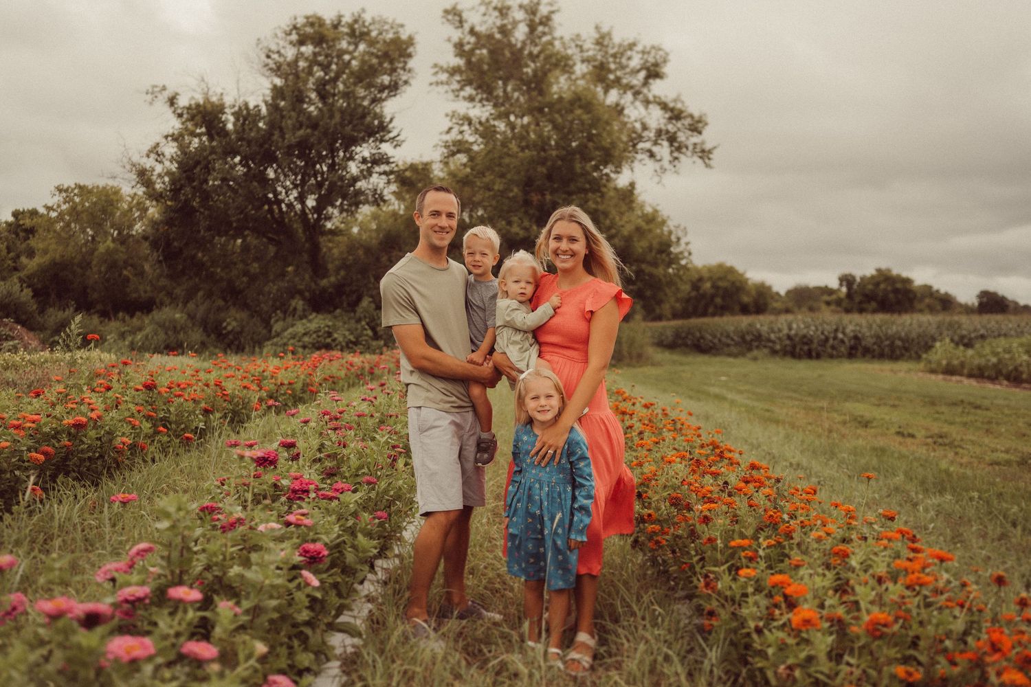 Family portrait session among vibrant wildflowers at the edge of a field.