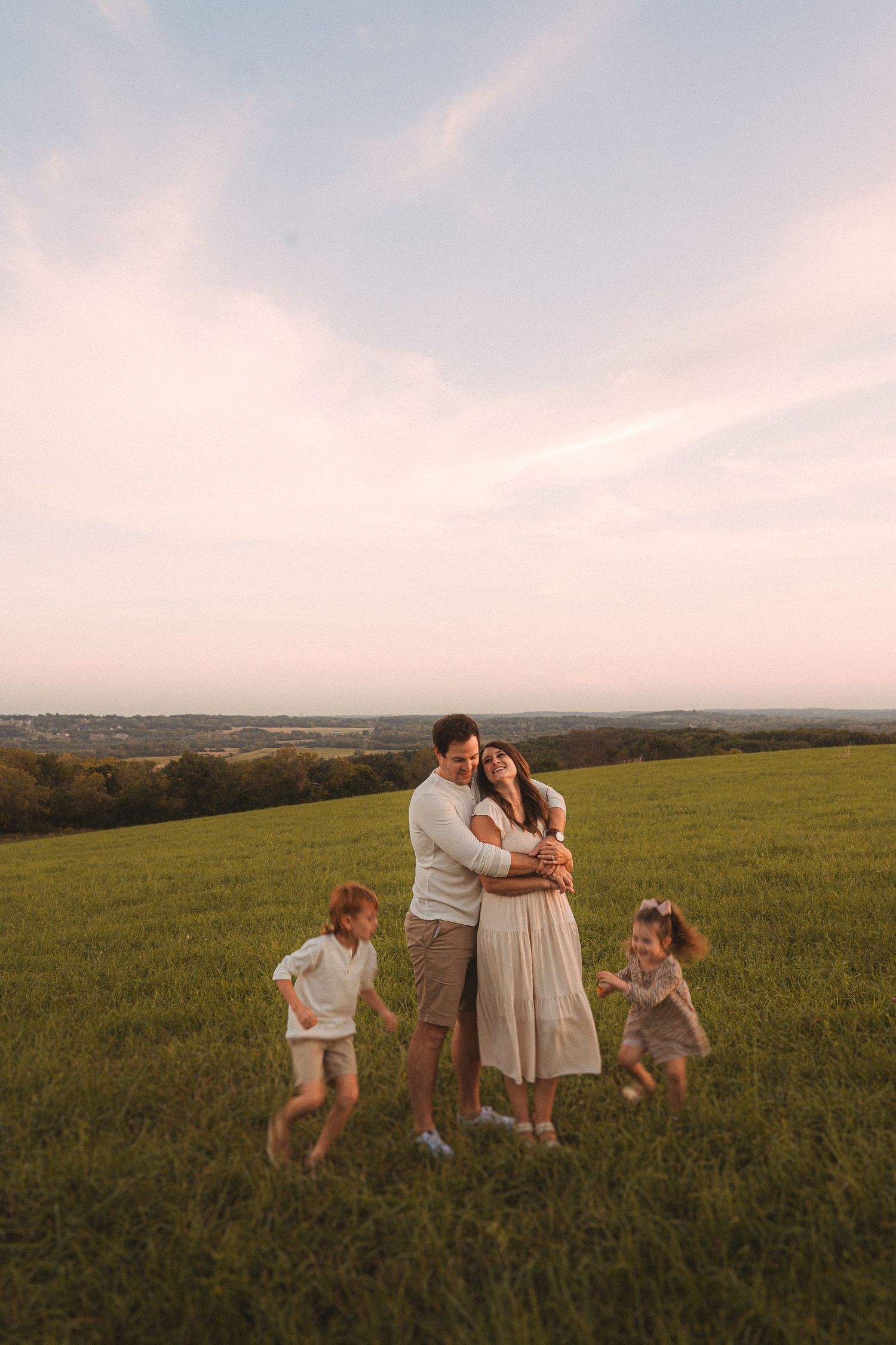 Family spending time together in a scenic hilltop meadow at sunset.