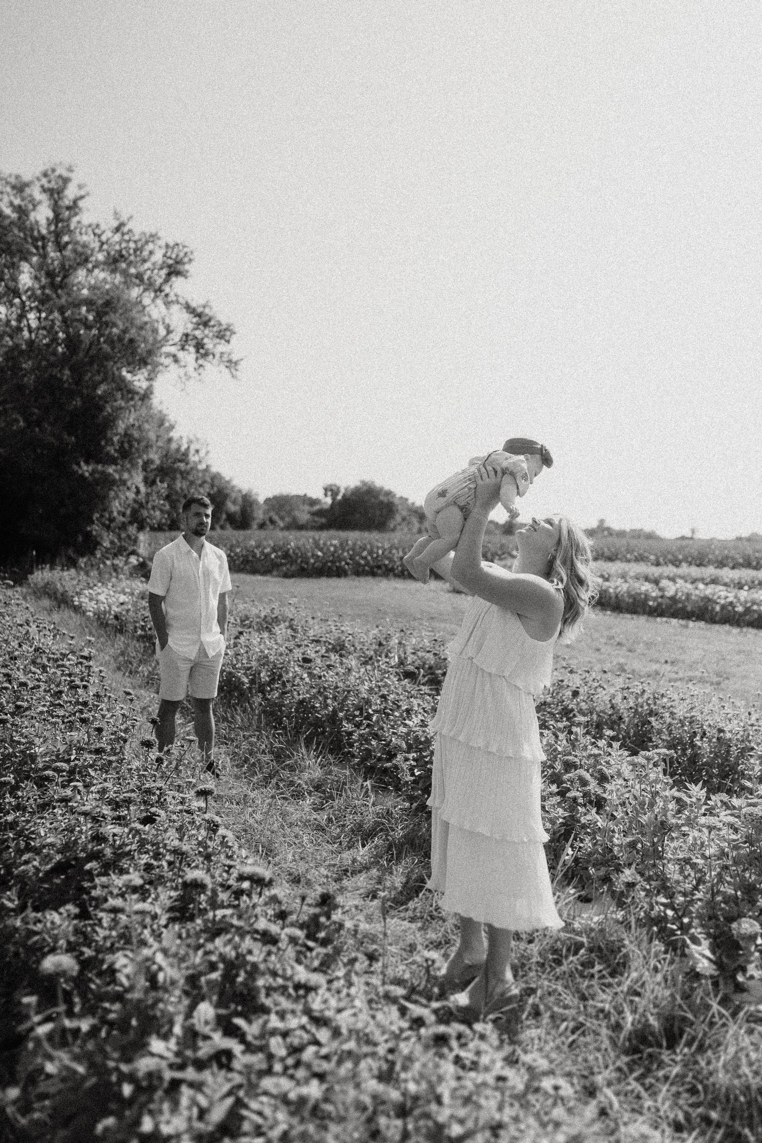 Black and white photo of people in a lush field on a sunny day.