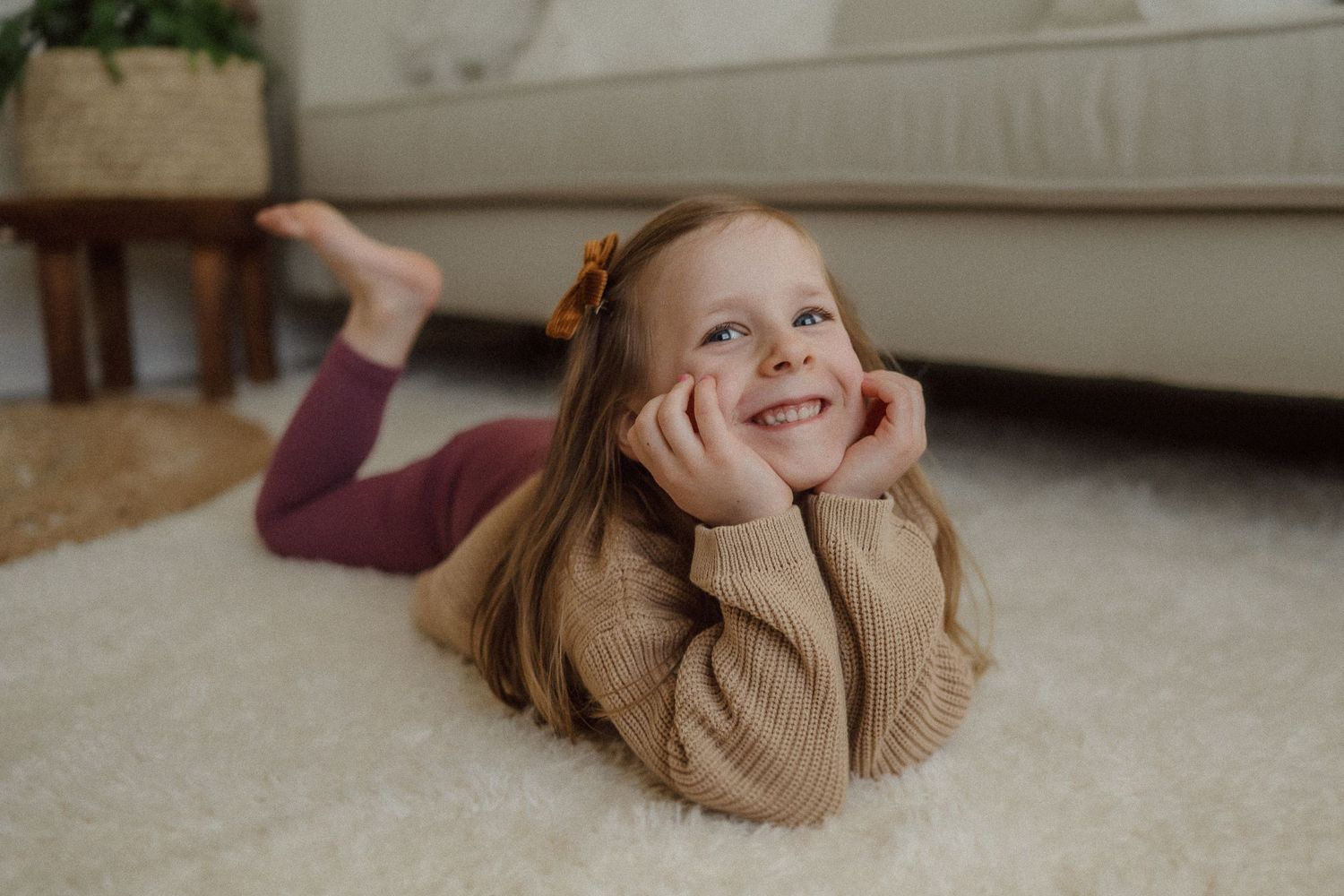 Cheerful pose on carpet wearing cozy brown knit sweater during indoor photoshoot.