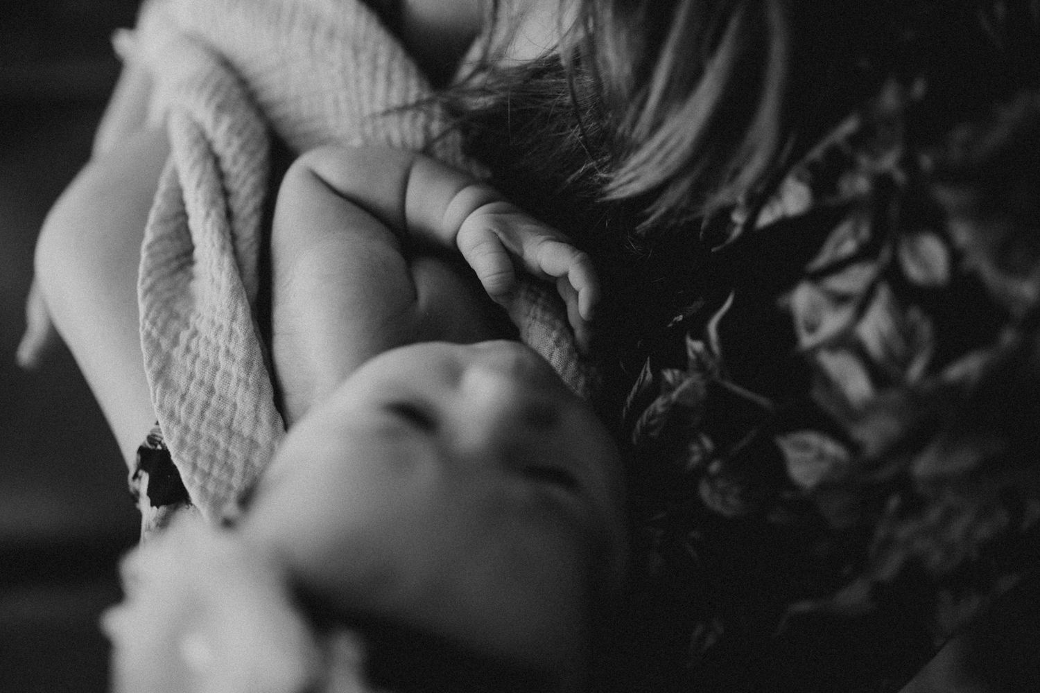 Intimate black and white close-up of a baby wrapped in textured blanket.