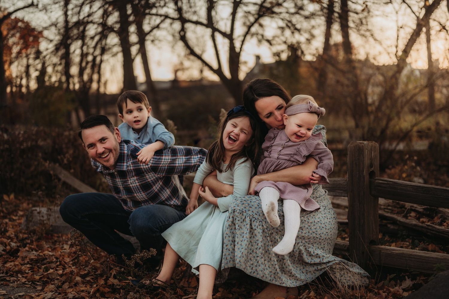 A playful family portrait taken outdoors during autumn golden hour.