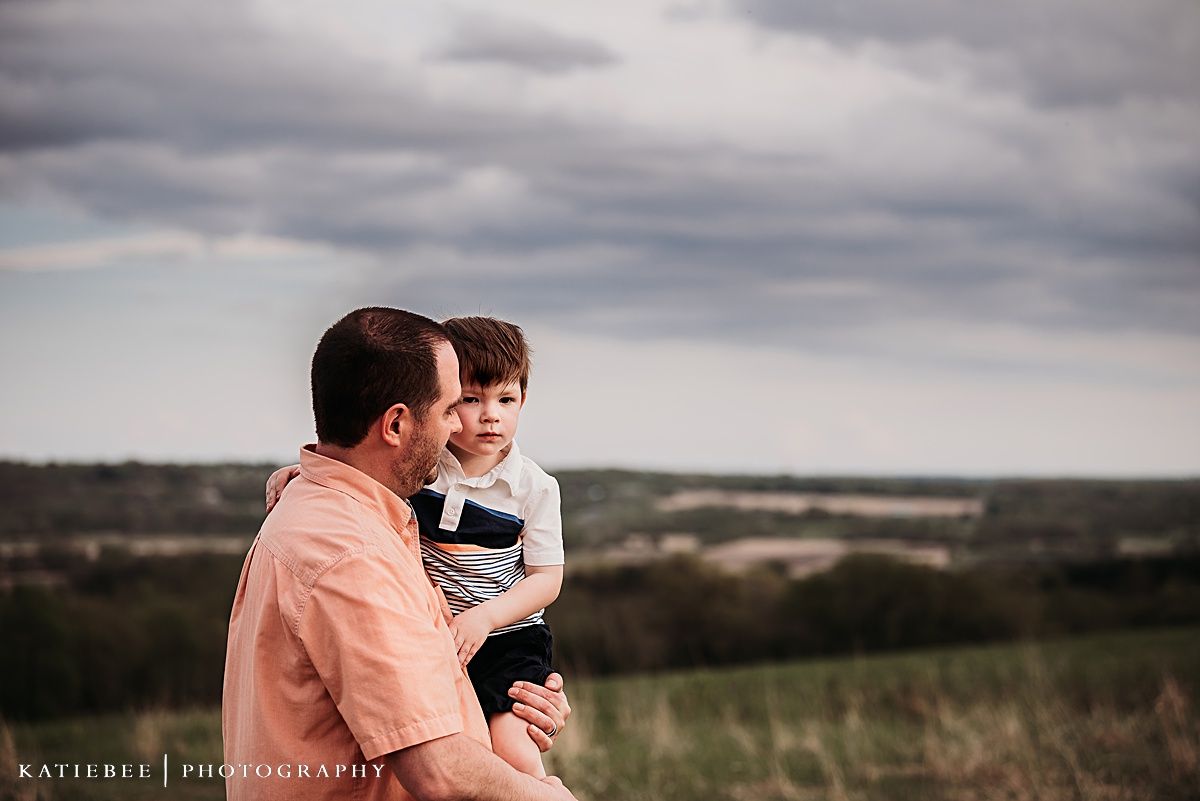 A heartwarming candid moment between parent and child photographed on a hilltop.