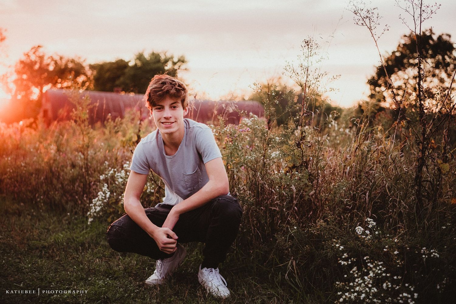 Portrait of a teen sitting in a wildflower field at sunset.