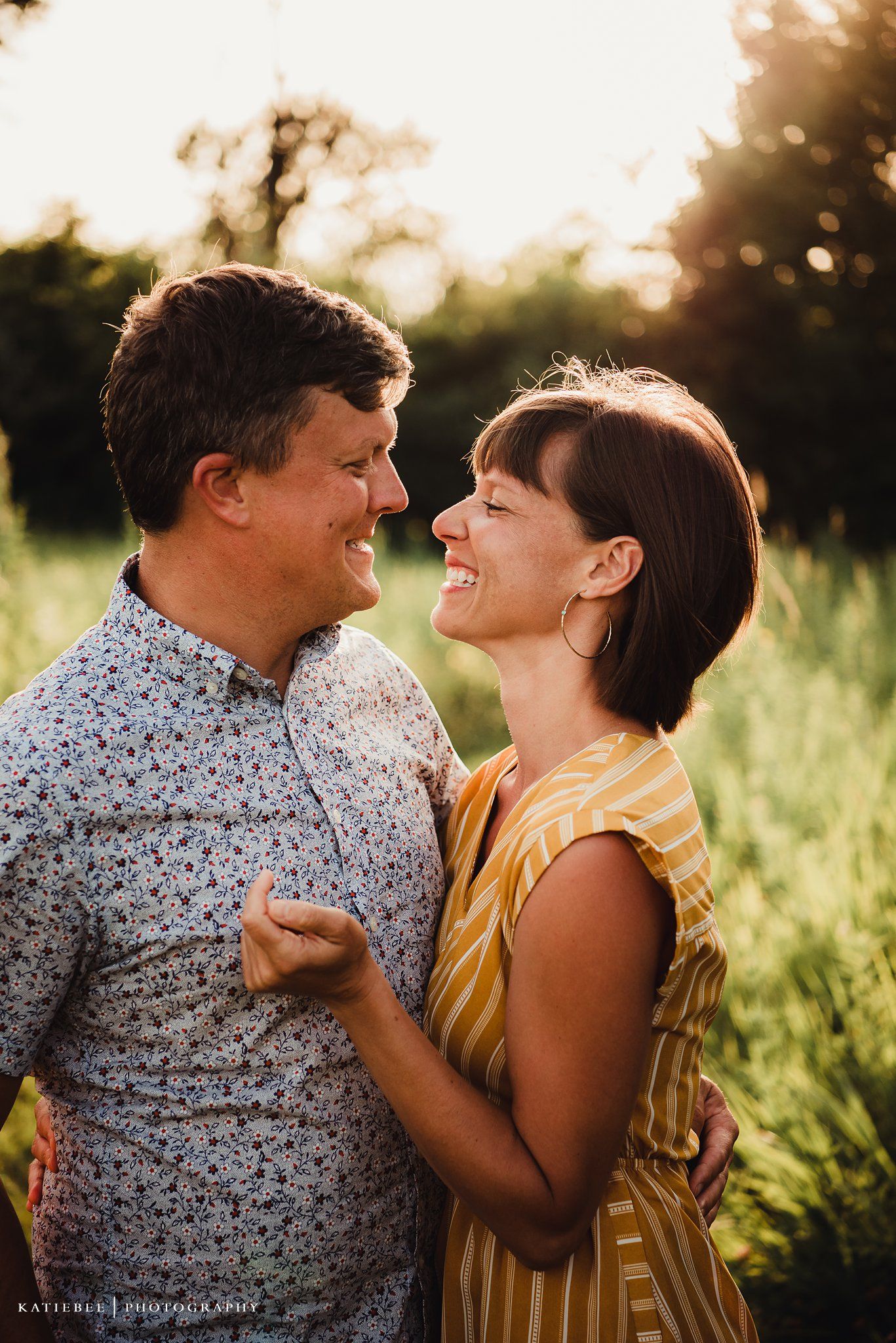 Intimate portrait of a couple laughing together in golden sunlight.
