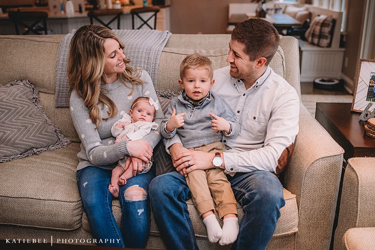 Intimate family moment captured on a comfortable grey sofa in a warm-toned living room.