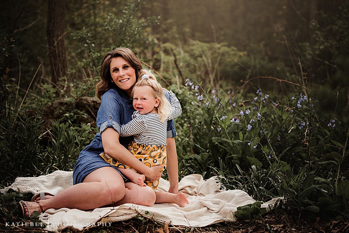 Two people share a peaceful moment together while sitting on a blanket surrounded by spring flowers.