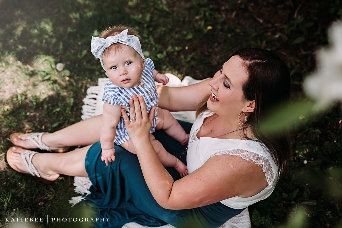Joyful outdoor portrait of parent and baby playing together on a blanket.