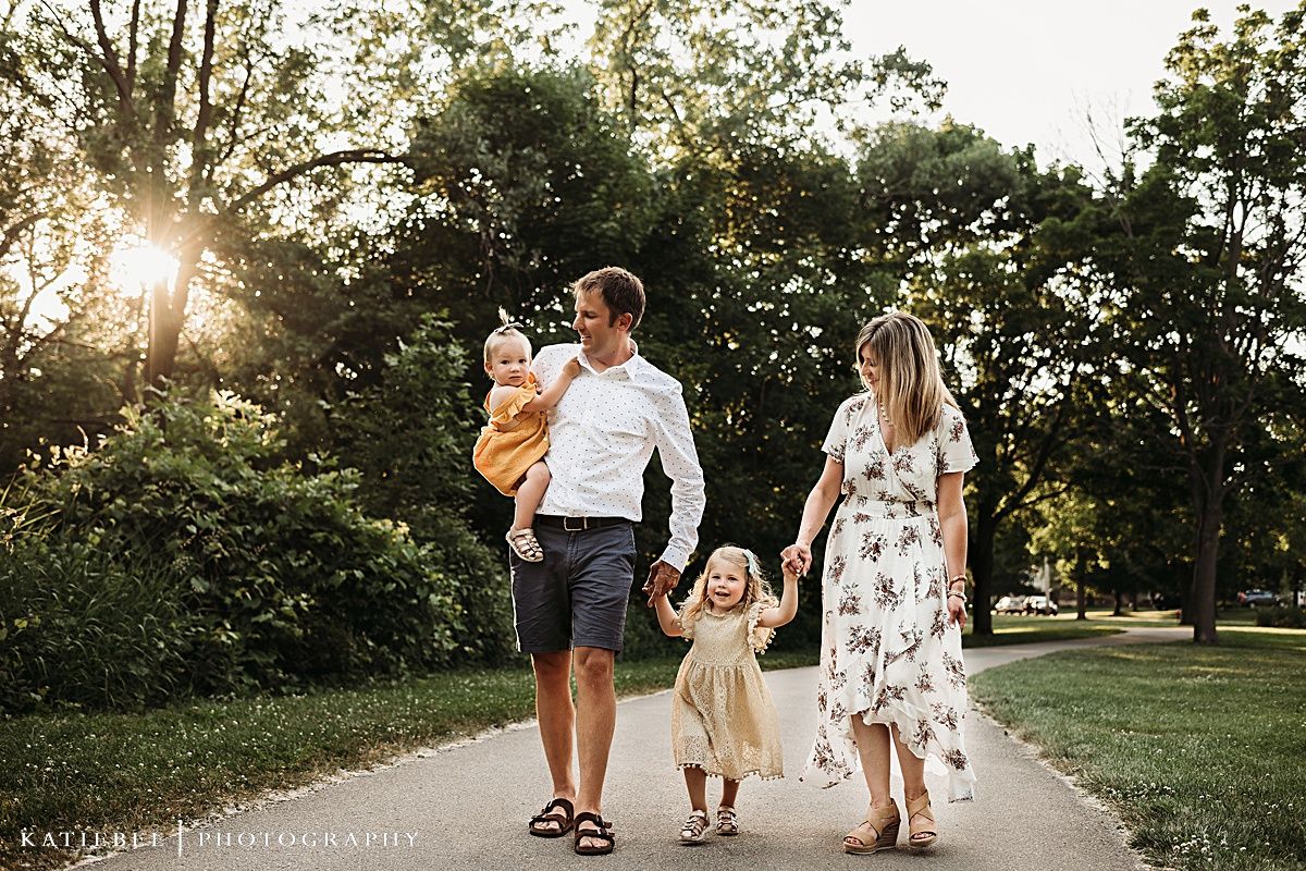 Family walking together on path through park at golden hour.