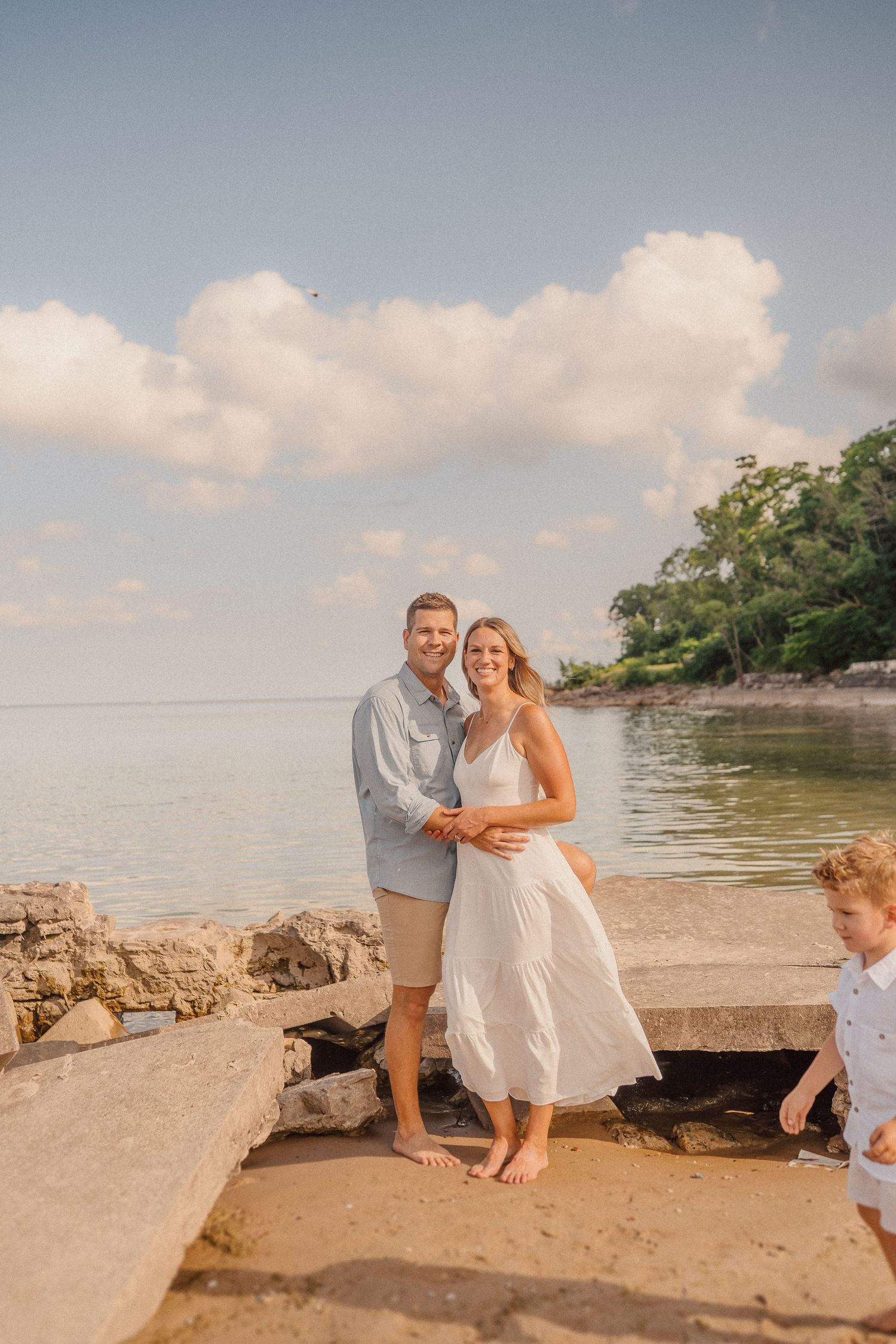 Family portrait session at lakeside beach with natural rocky landscape.
