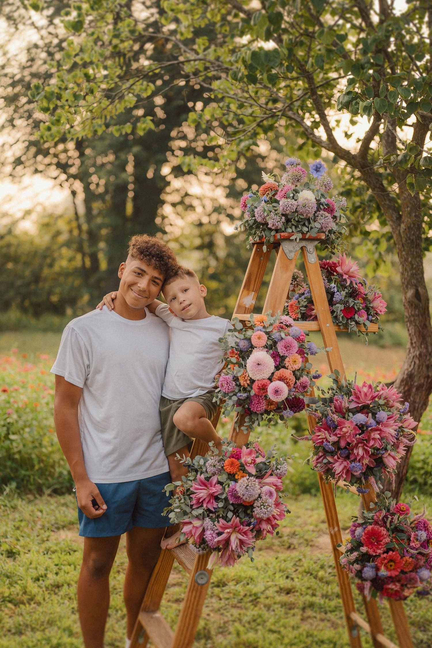 Beautiful floral ladder display with pink and purple blooms set up outdoors in a garden setting during golden hour.