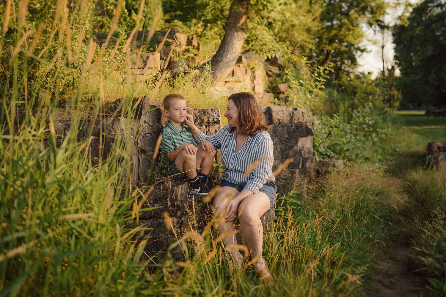 Candid family moments captured in tall grass during sunset.