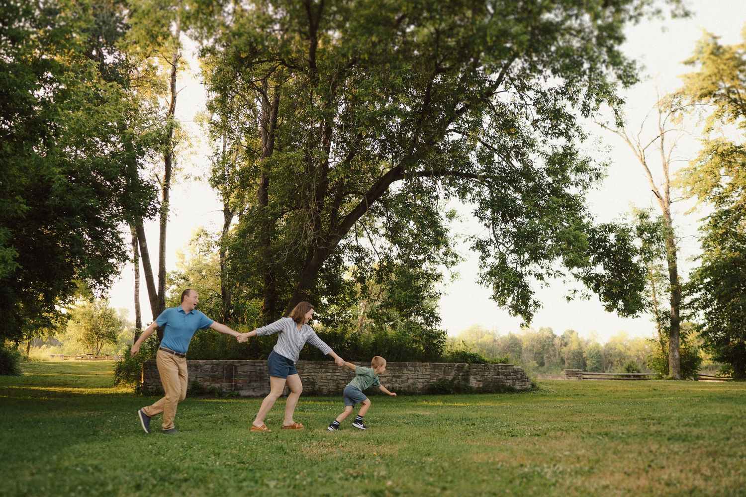 Family shares playful moments together on a grassy hill during sunset at an outdoor photo session.