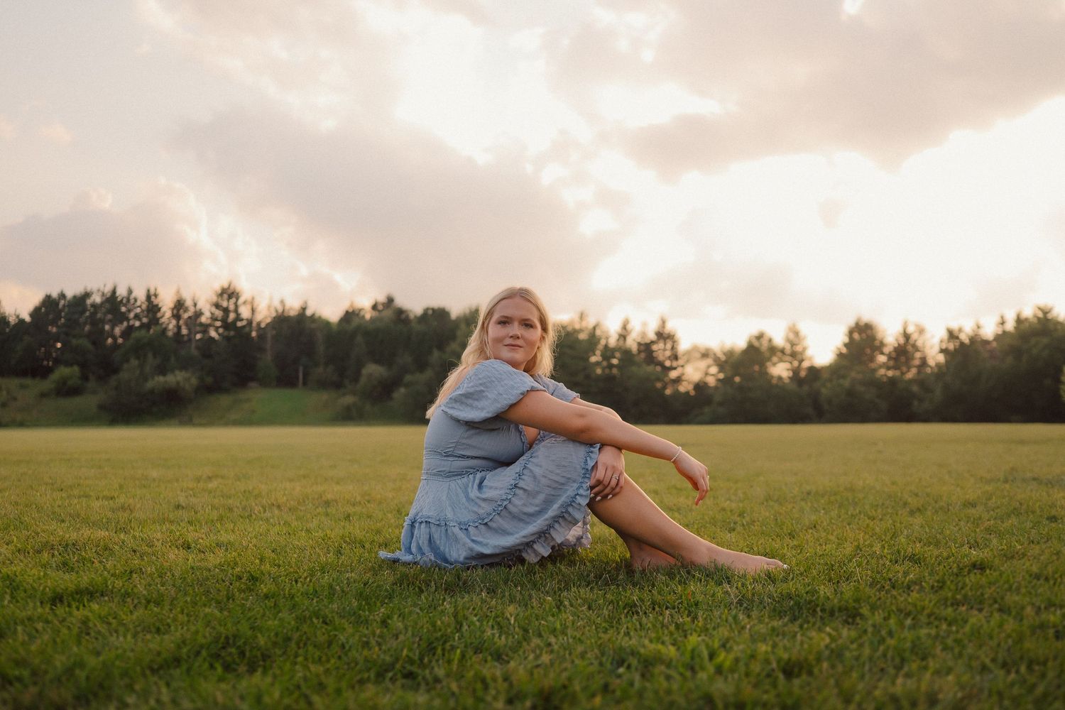 Person relaxes in grassy field during golden hour sunset.