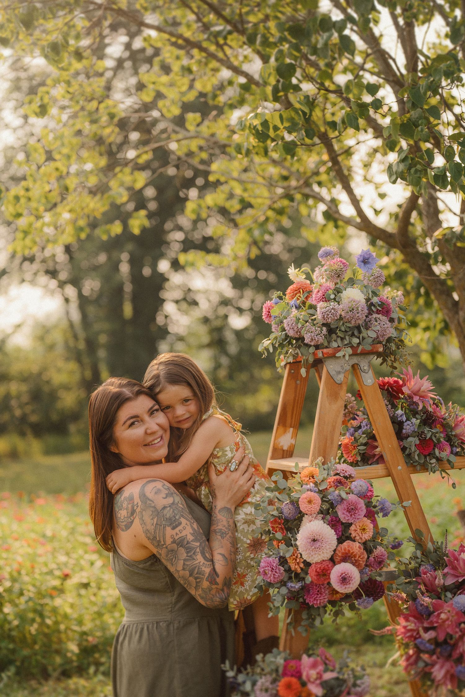 A tender moment captured in a garden setting with a wooden ladder adorned with pink and purple flowers.