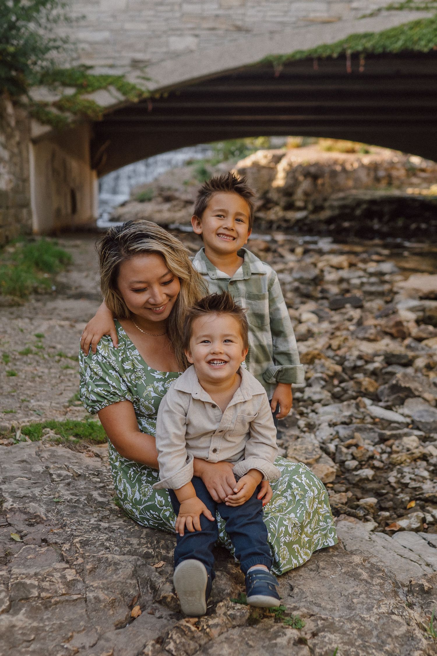 A heartwarming outdoor photoshoot showing playful moments between parent and child on a rocky ground.