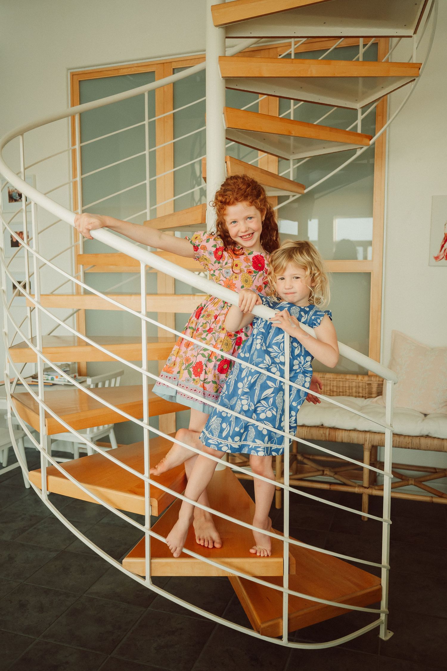 Children in matching blue dresses play and pose on wooden stairs in a sequence of candid shots.
