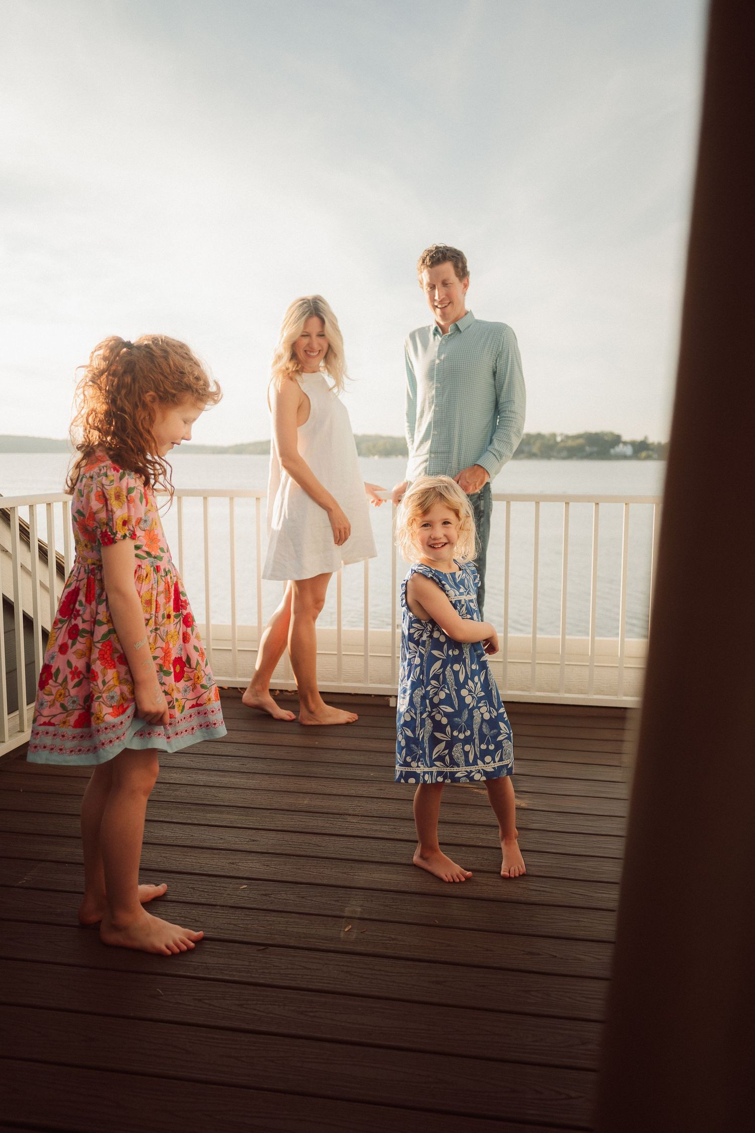 Children playing and dancing on a wooden deck during golden hour.