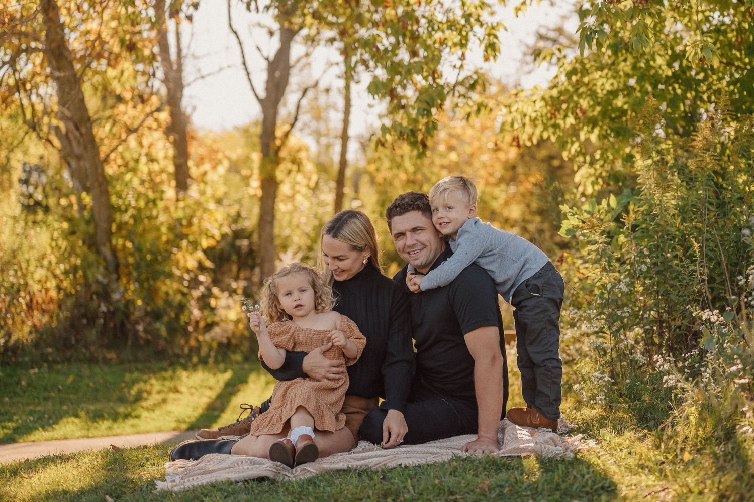 Family relaxing together on blanket during outdoor autumn photoshoot.