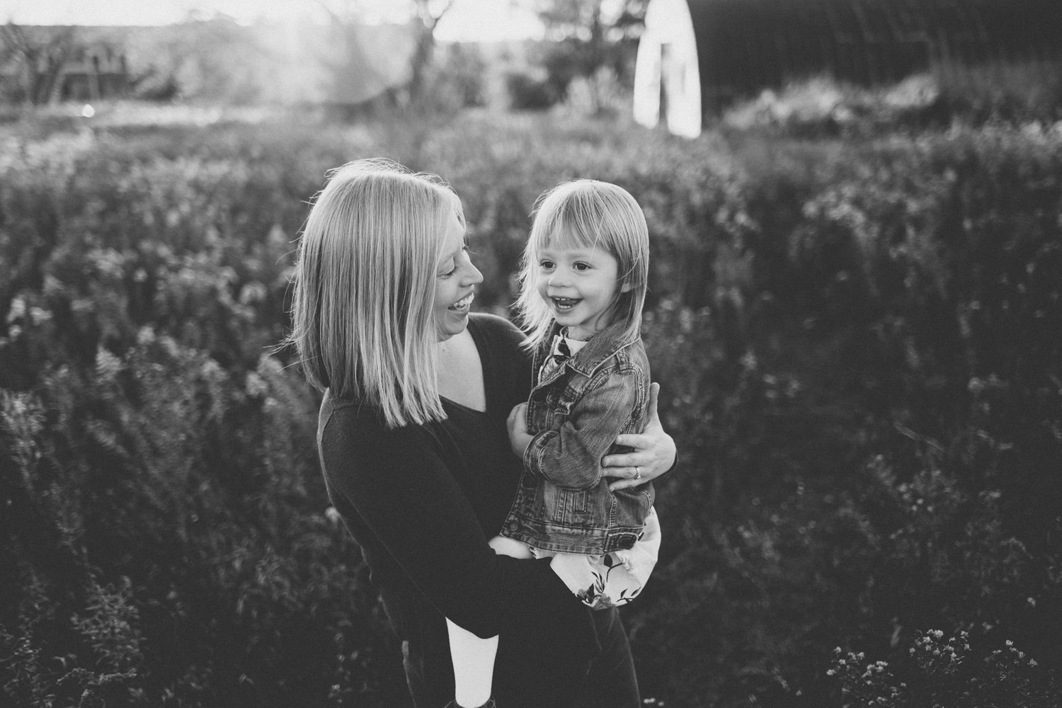 Black and white intimate portrait of parent and child against natural backdrop.