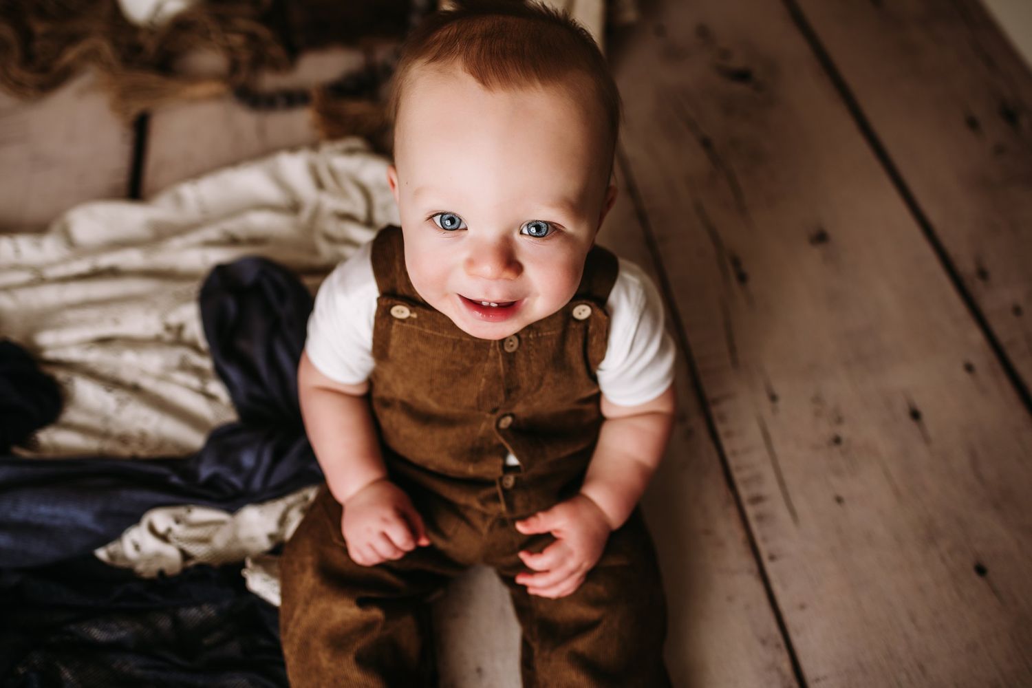 Happy moment captured in brown overalls against rustic photography setup.