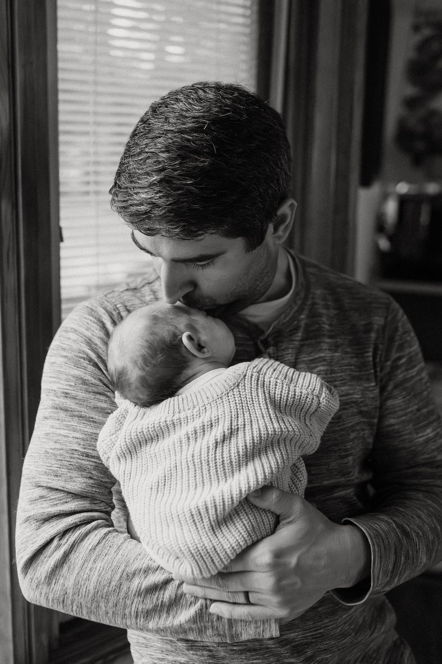 Black and white series of tender moments between parent and infant in matching knit sweaters.