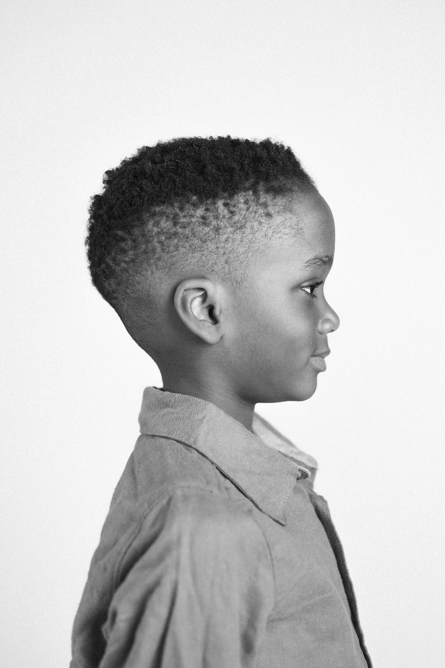 Black and white profile portrait of a young child in a collared shirt against a light background.
