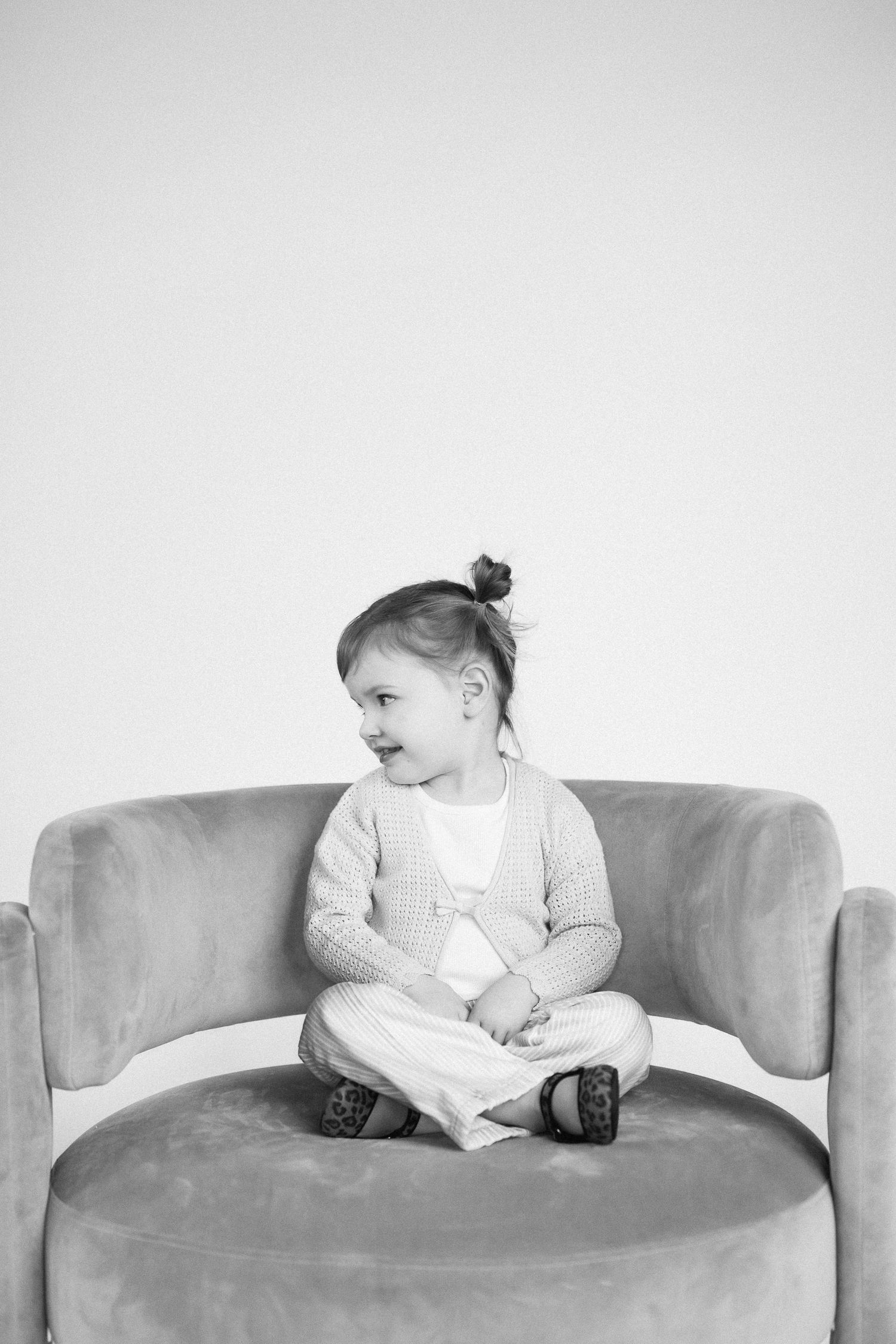 Four sequential black and white photos capturing different poses on a modern curved sofa.