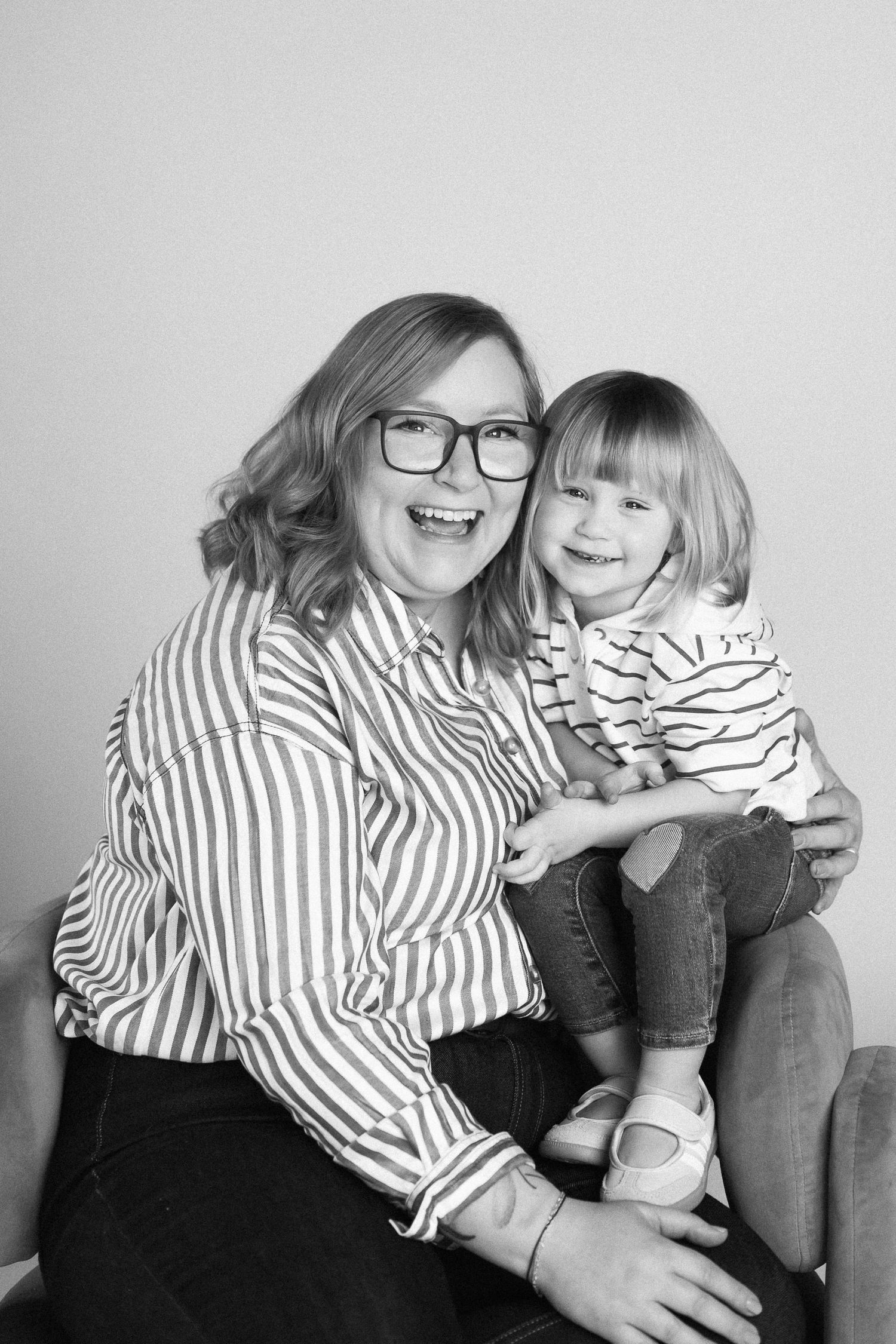 Black and white photo series showing joyful moments of laughter and bonding in matching striped shirts.