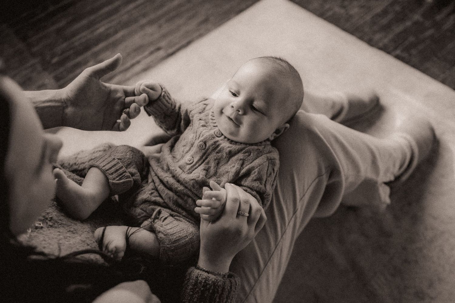 A series of black and white photos showing a baby lying down and playing with toys in different poses.