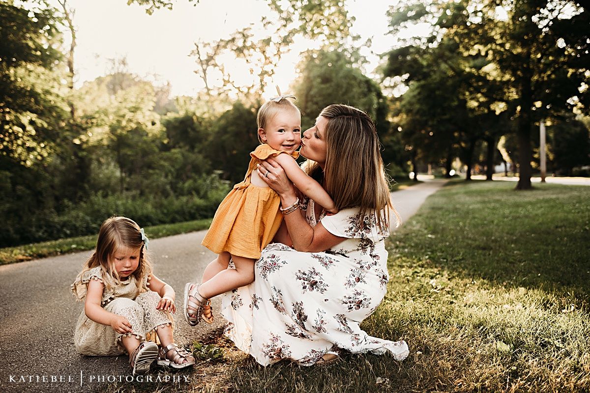 Outdoor family portrait with floral dress and mustard yellow outfits sitting on grass during golden hour.