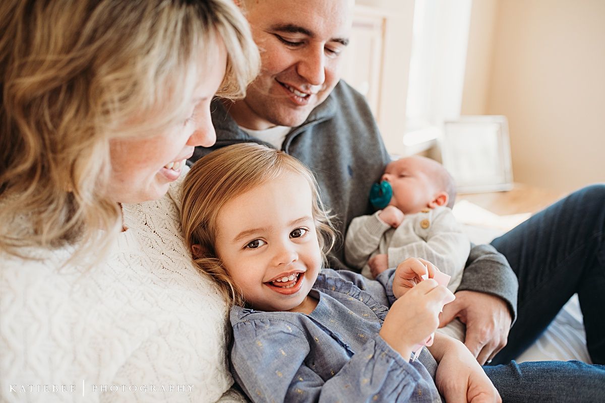 A family shares a joyful moment together on a couch with their infant.
