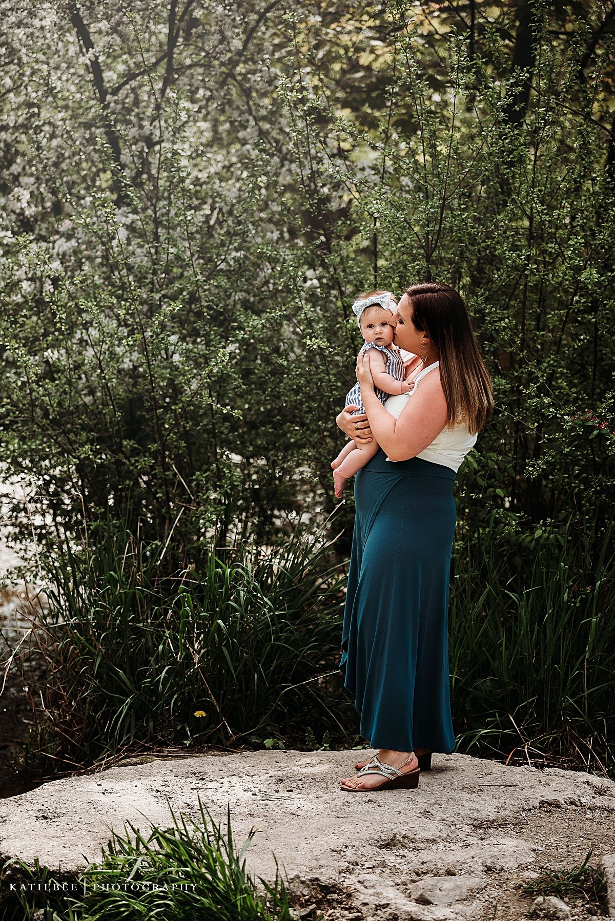 A touching outdoor portrait of parent and child standing in a lush garden with blooming white flowers.