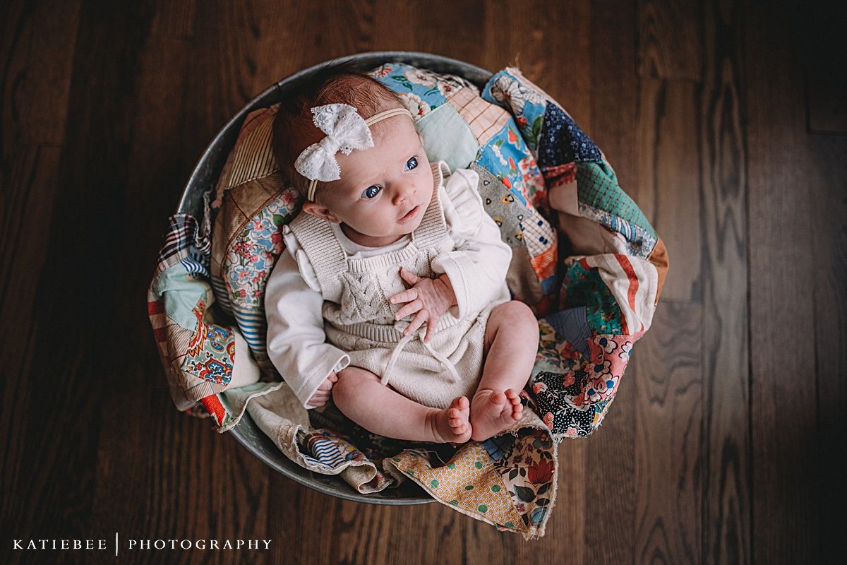Overhead view of a baby in white clothing sitting in a floral patterned chair.